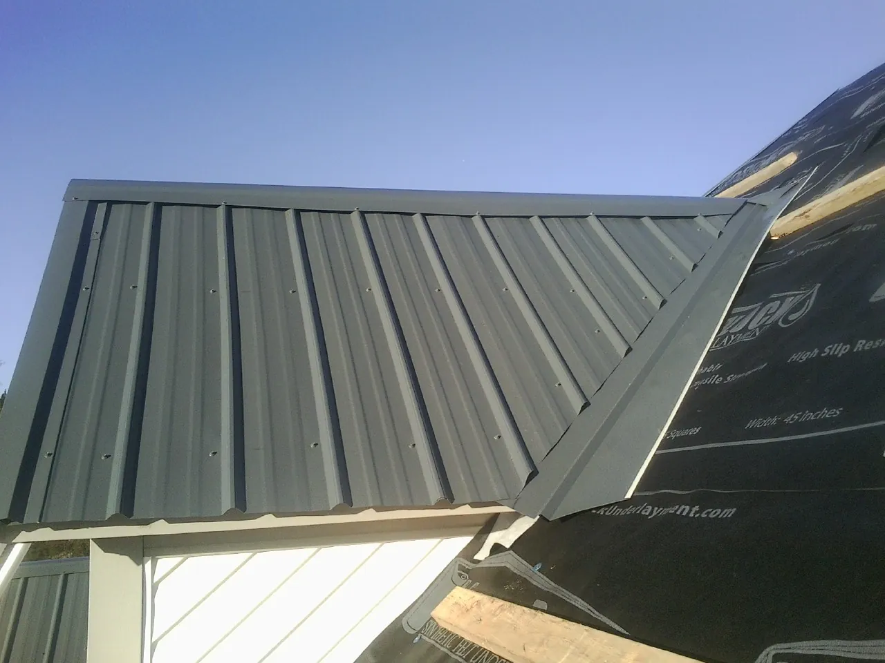 Gray metal roof panels going on over a garage gable in Disputanta