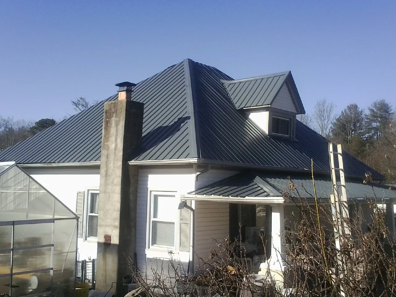Dark blue standing seam metal roof on a white farmhouse with dormer — Slate & Tile Roof Repair by Roofing Brothers in Disputanta