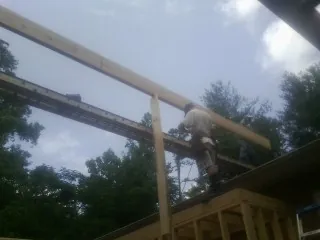 Carpenter setting a ridge beam over a new addition frame — Ice Dam Removal by Roofing Brothers in Disputanta