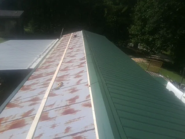 Old rusted panels beside newly installed green metal roofing — Wind Damage Roof Repair by Roofing Brothers in Disputanta