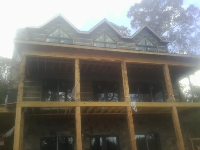 Dormers and porch framing on a large log home under construction — Roof Coating work by our crew in Disputanta