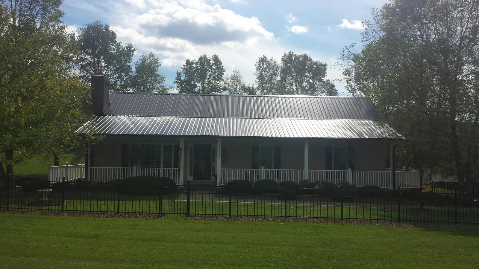 Gray metal roof on a brick ranch with a full width front porch — Gutter Guard Installation work by our crew in Disputanta