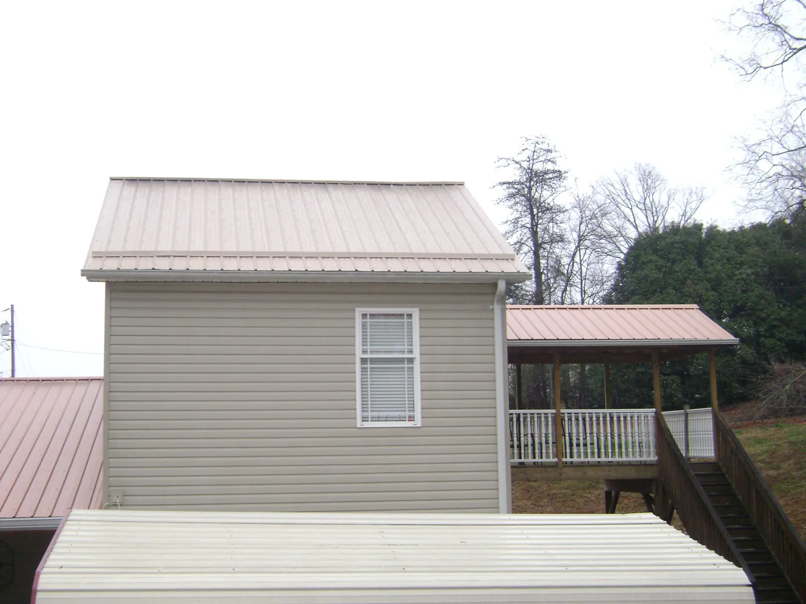 Tan metal roofs on a two story addition and attached porch, from a Roof Replacement job in Disputanta