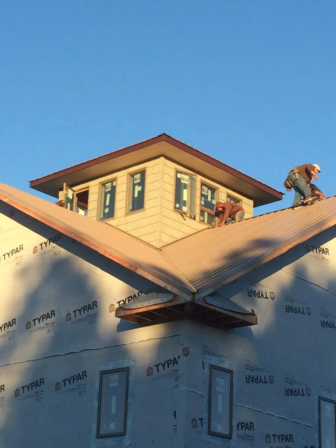 Roofers working around a rooftop cupola on a new metal roof at sunset — Roof Waterproofing in Disputanta by Roofing Brothers